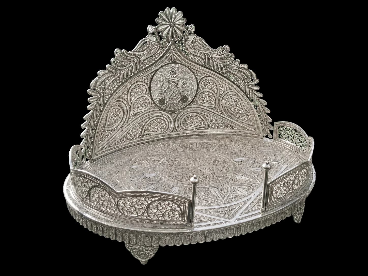 Round silver filigree serving stand with a tall ornamental back framed by peacock motifs