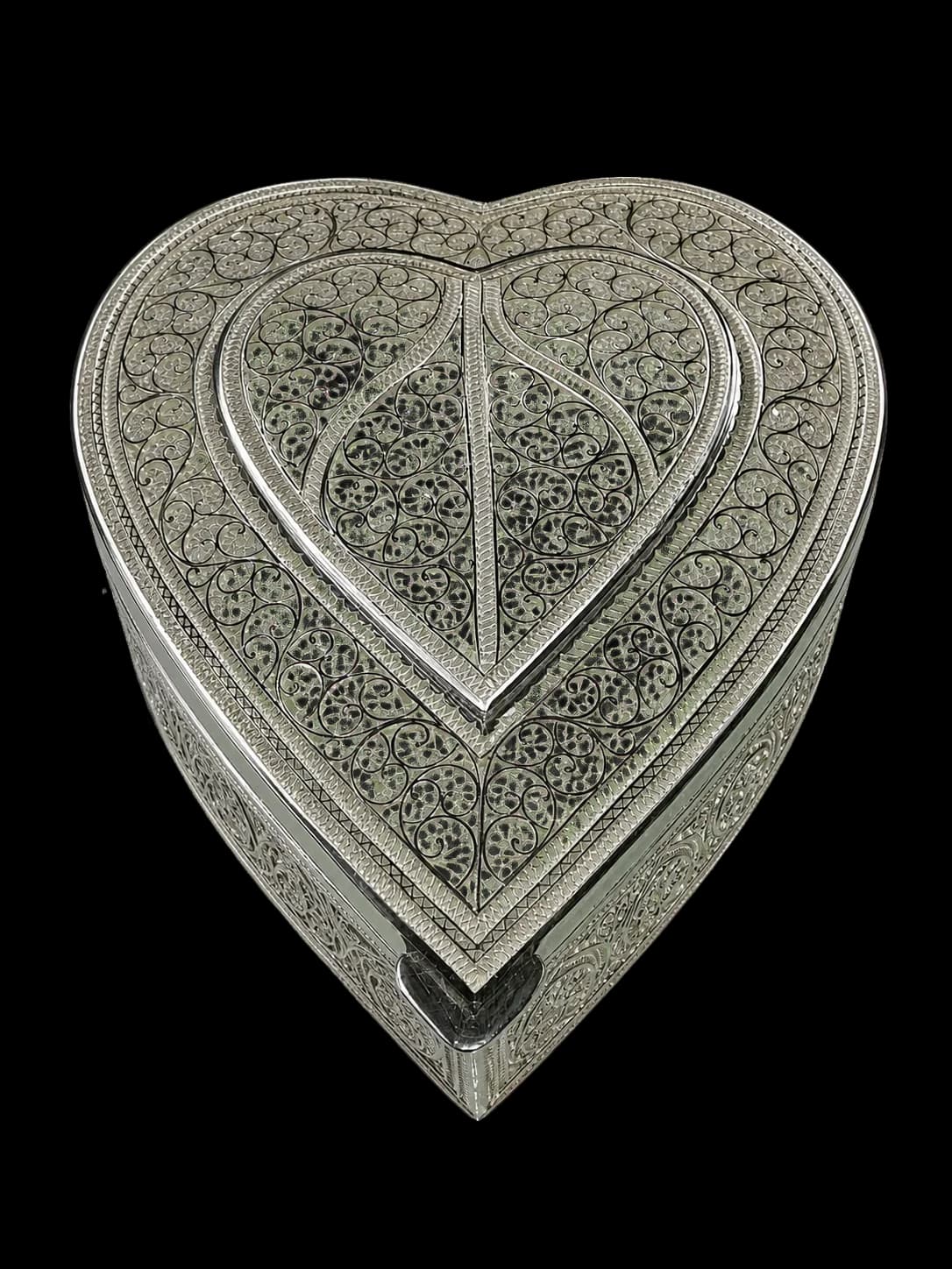 Deep heart-shaped silver filigree box with layered heart motifs across its lid
