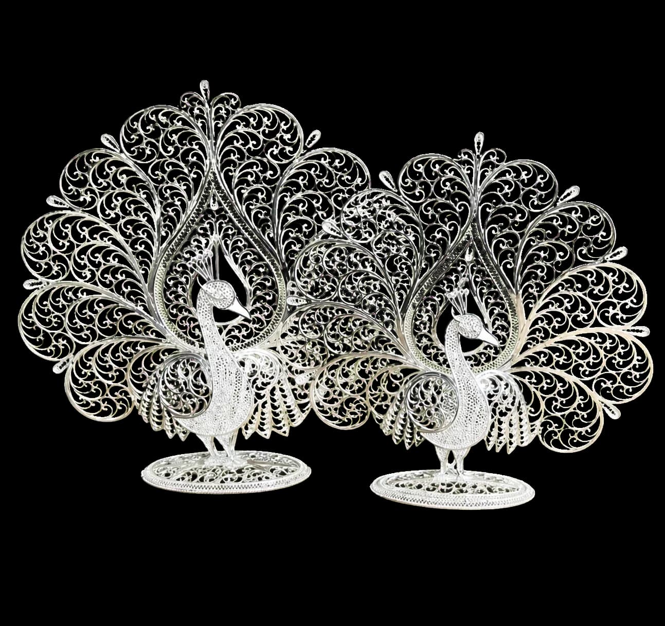 Two silver filigree peacocks facing one another in a decorative composition